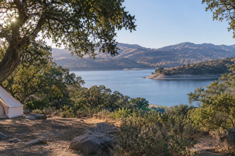 Canvas tent beneath oak trees overlooking calm Lake Cachuma