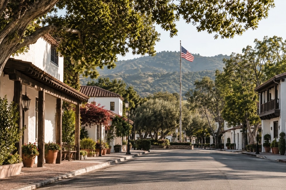 A quiet small-town street framed by trees and whitewashed architecture